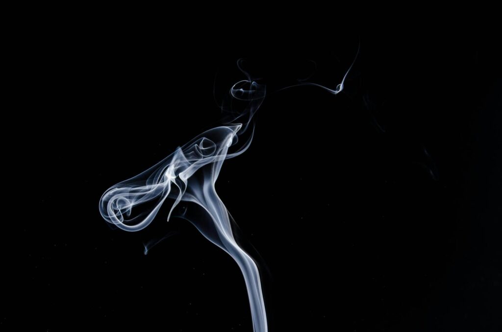 Artistic photo of white smoke swirls on a black backdrop.