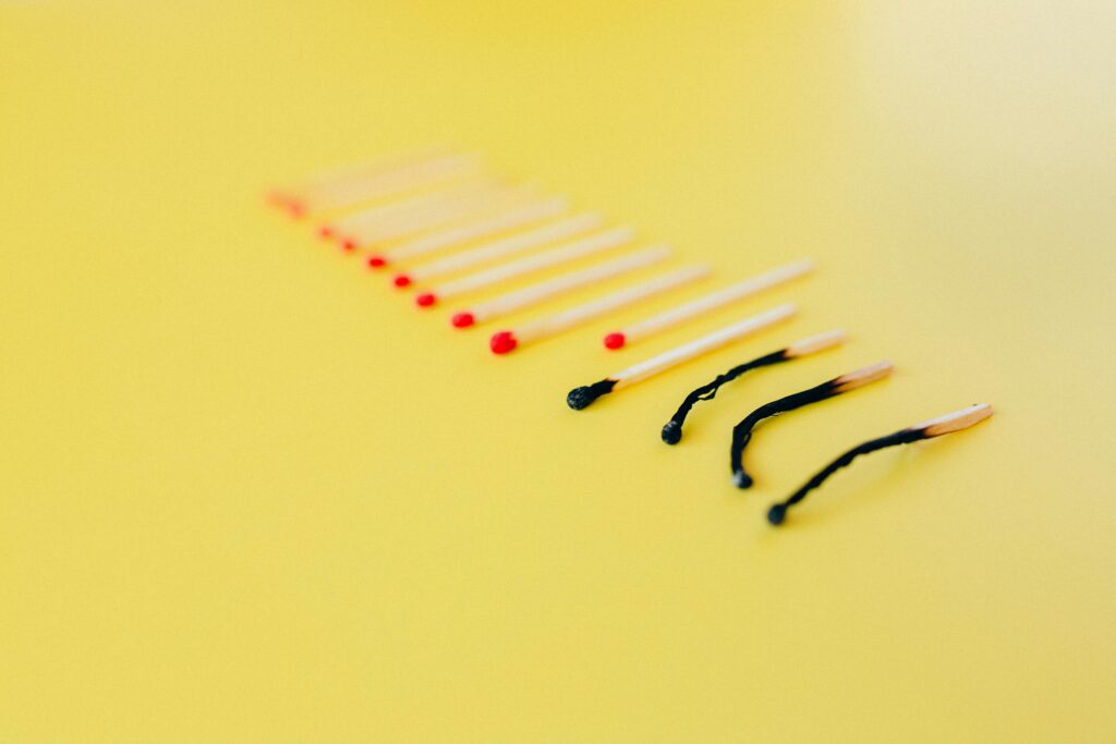 Symbolic representation of burnout using matches on a yellow background, illustrating exhaustion.